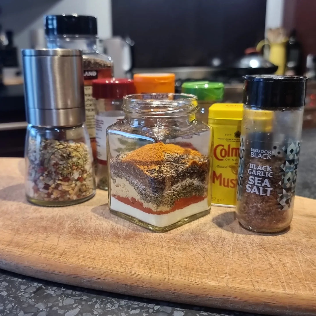 a jar with layered spices surrounded by salt and other spices