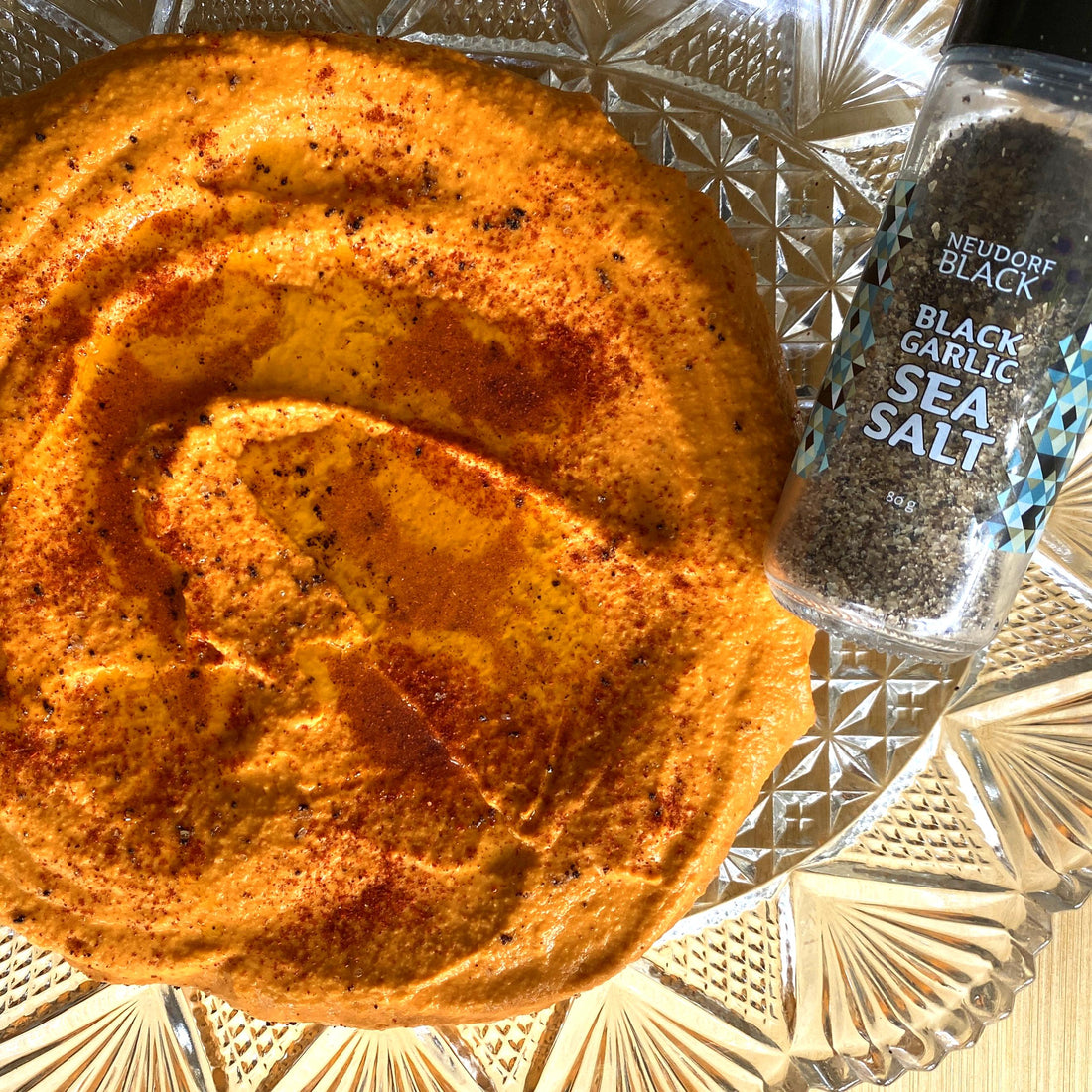 a reddish hummus with black garlic sea salt shaker beside it