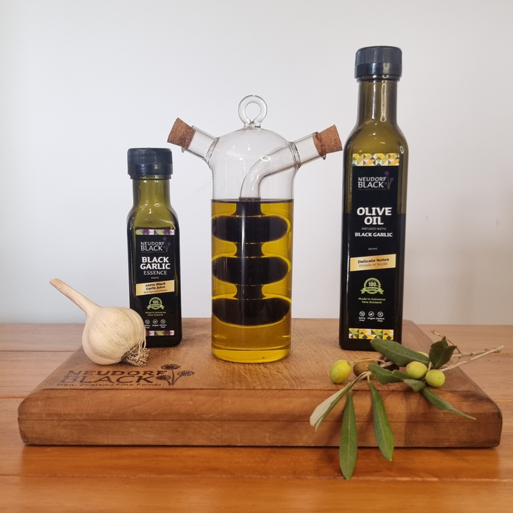 Oil and Essence bottles beside a glass decanter that is filled with Black Garlic oil and Black Garlic essence