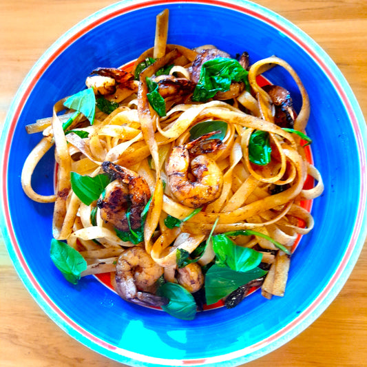 pasta topped with prawns and greens in a colourful bowl