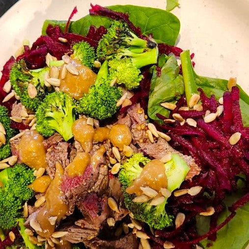 Golden black honey hummus on top of a steak salad