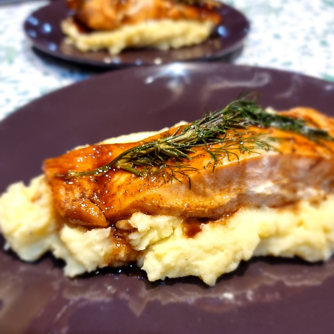 Salmon fillet drizzled with black honey sitting on a bed of mashed potato