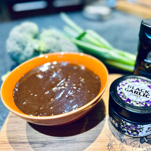 deep brown sauce in a bowl beside a jar of black garlic puree