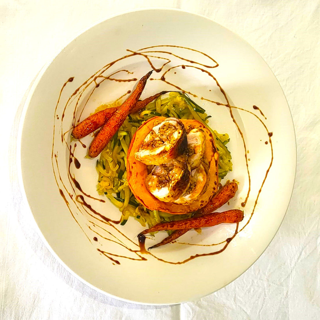 black honey chicken roulade on a round plate