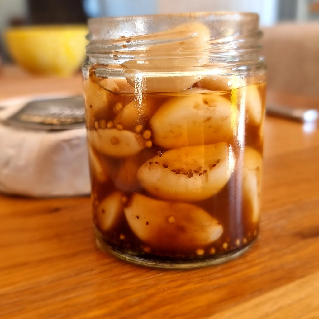 pickled garlic in black garlic honey, in a jar