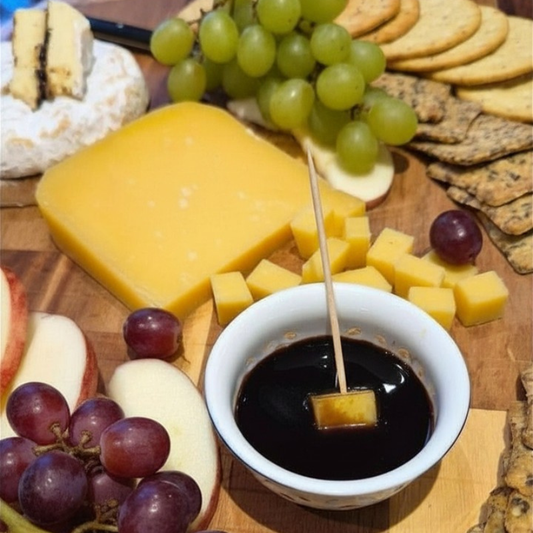 cubes of gruyere cheese beside black garlic balsamic glaze on a cheeseboard