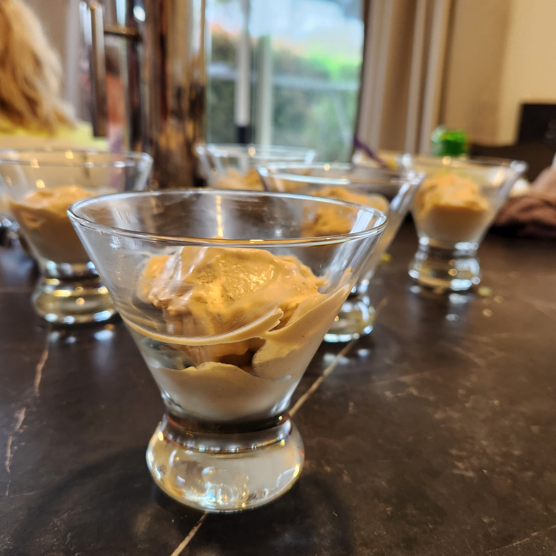 Black honey ice cream in a glass tumbler.