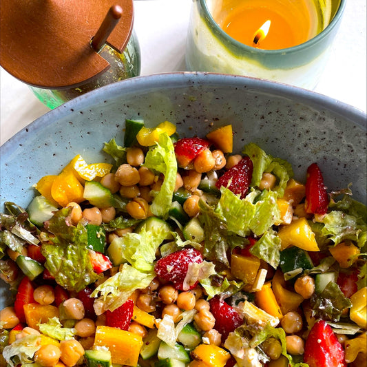 colourful salad with container of black honey vinaigrette beside
