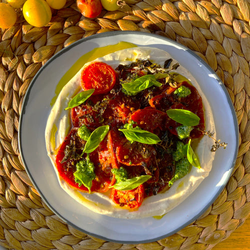 roasted tomatoes with fresh basil piled on a round plate