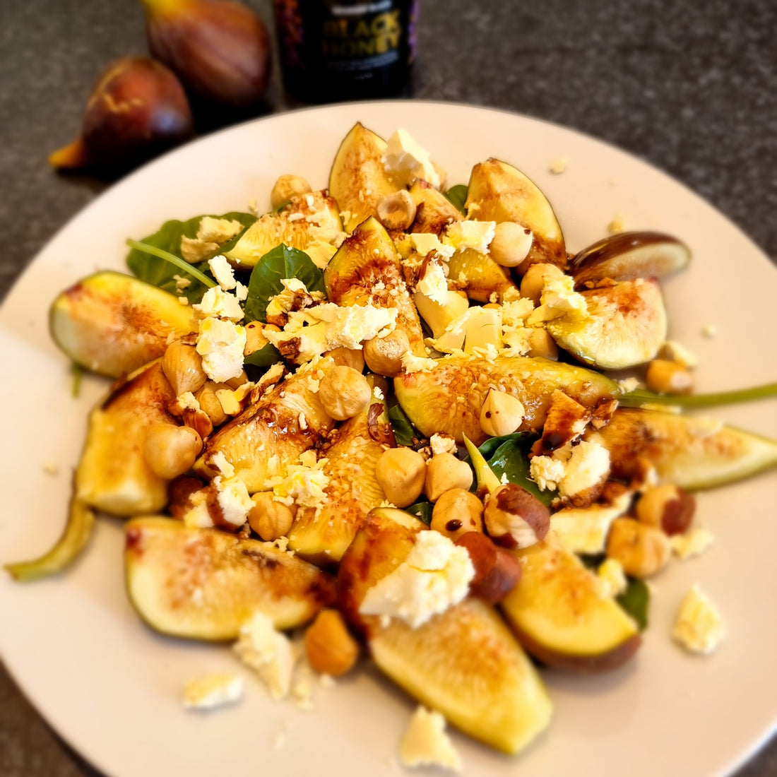 fresh figs on a plate with nuts, feta and greenery