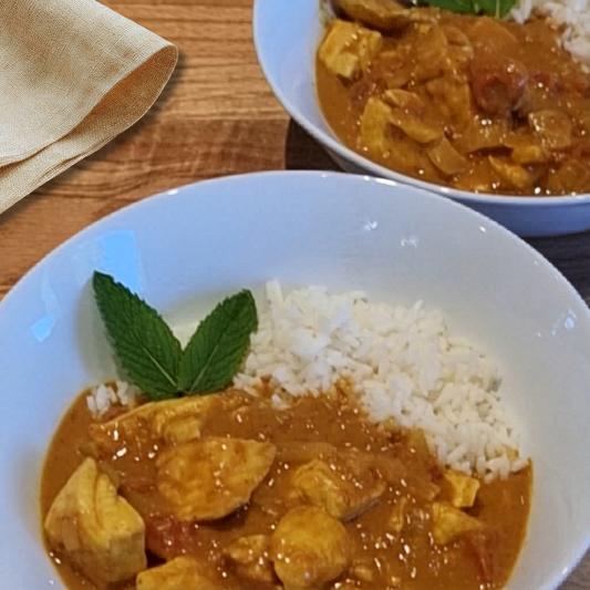 2 bowls with fish curry and rice on a table