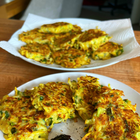 crispy zucchini fritters on a plate sprinkled with black garlic sea salt