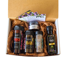 Cardboard box packed with a jar of Black Garlic Puree, BBQ sauce, Black Honey, Salt Shaker, Black Garlic Essence and some recipes