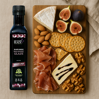 Neudorf Black Garlic Balsamic Glaze bottle with a charcuterie board featuring cheese, figs, crackers, and prosciutto.