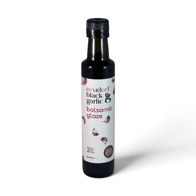 A bottle of Neudorf Black Garlic Balsamic Glaze on a clean white background. The product is in a dark glass bottle with a black cap and a white label featuring illustrations of garlic cloves.