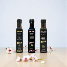 Three bottles of Black Garlic products on a light surface with a light blue background